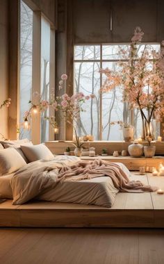 a bedroom with candles and flowers in vases on the windowsill next to a bed