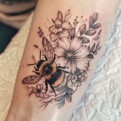 a bee and flowers tattoo on the leg