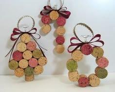 three wine cork ornaments with bows on each ornament, one is shaped like a wreath