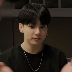 a young man wearing a black shirt and silver necklace