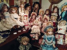 a group of dolls sitting next to each other on top of a wooden table in front of a mirror