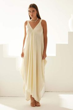 Cream modal asymmetrical maxi dress with a V neckline. - Aza Fashions Summer Flowy Floor-length V-neck Dress, Elegant Summer Maxi Dress With Asymmetrical Neckline, Chic Asymmetrical Neckline Summer Maxi Dress, Elegant Vacation Maxi Dress With Asymmetrical Neckline, Elegant Asymmetrical Dress With Asymmetrical Neckline For Vacation, Chic Summer Maxi Dress With Asymmetrical Neckline, Elegant Asymmetrical Dress For Vacation, Elegant Beach Maxi Dress With Asymmetrical Neckline, Elegant Asymmetrical Neckline Maxi Dress For Beach