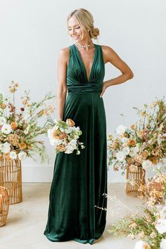 a woman standing in front of flowers wearing a green dress