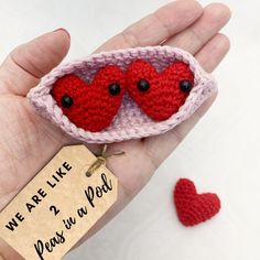 a hand holding a tiny crocheted heart with two hearts in it and a tag that says we are like 2 peas in a pod