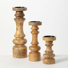 three wooden candlesticks sitting next to each other on top of a white surface