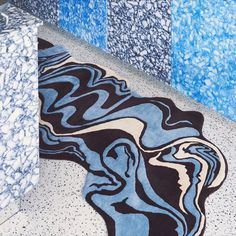 a bathroom with blue and black tiles on the floor, rugs in the shape of waves