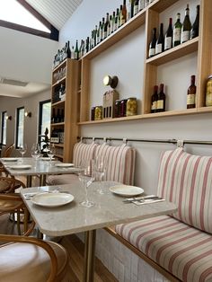 there are many bottles and glasses on the shelves above the tables in this restaurant that is empty