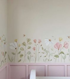 a baby's room with pink walls and flowers painted on the wall, along with a crib