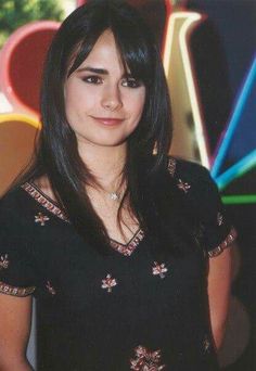 a young woman standing in front of some colorful wallpaper and looking at the camera