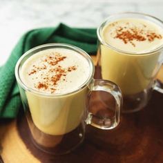 two mugs filled with liquid sitting on top of a wooden tray