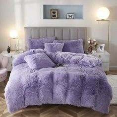 a bed with purple comforter and pillows in a room