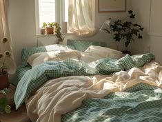 an unmade bed with green and white checkered comforter in a sunny room