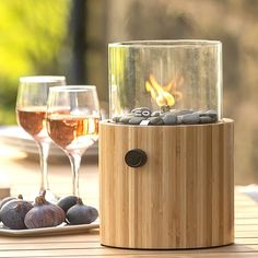 two glasses of wine sitting on top of a wooden table next to rocks and stones