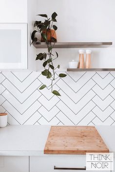 a kitchen counter with a cutting board and potted plant on it next to shelves