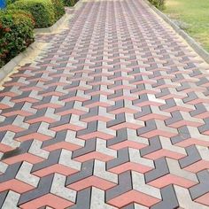 a brick walkway with grass and bushes in the background