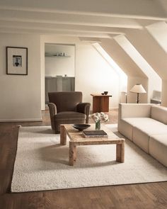 a living room filled with furniture next to a white couch and coffee table on top of a hard wood floor