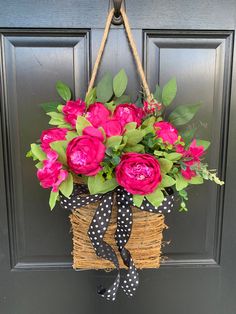 a basket filled with pink flowers hanging from a door