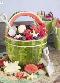 a watermelon bucket filled with lots of different types of food on top of a table