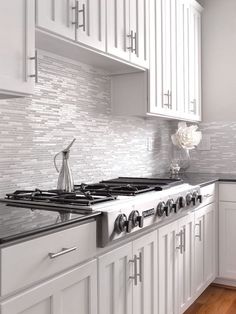 a kitchen with white cabinets and black counter tops is pictured in this image, the stove has a tea kettle on it