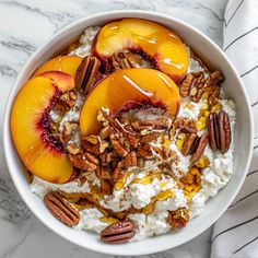 a bowl filled with oatmeal topped with sliced peaches and pecans