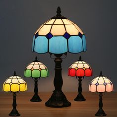 four different colored lamps sitting on top of a wooden table