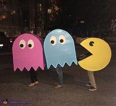 three people are standing in the street with fake ghost faces on their heads and hands