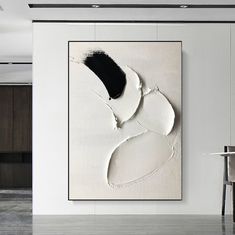 an abstract painting hangs on the wall next to a dining room table with chairs in it