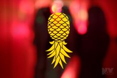 a blurry image of a yellow pineapple on a red background with people in the background