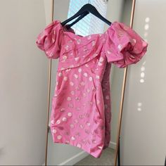 a pink top hanging on a clothes rack in front of a mirror with the reflection of a window behind it