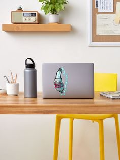 a laptop computer sitting on top of a wooden desk next to a yellow chair and potted plant