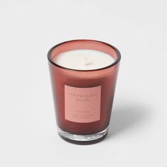 a candle with a label on it sitting in front of a white background that says strawberry musk