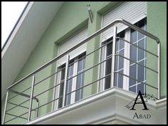 a green building with a metal balcony and balconies on the second floor, above which there is a sign that reads aaad