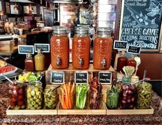 mason jars filled with pickles, carrots and other vegetables on a counter in a restaurant