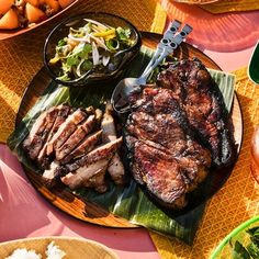 there is a plate with meat and vegetables on it next to other plates full of food