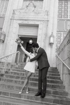 black and white photograph of a couple kissing on the steps in front of a building