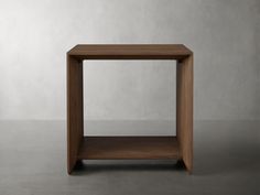 a small wooden table sitting on top of a cement floor next to a white wall