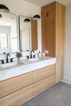 a bathroom with two sinks, mirrors and lights on the wall above them is shown