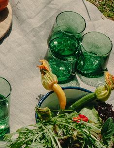 green glassware sitting on top of a table next to vegetables and other items in bowls