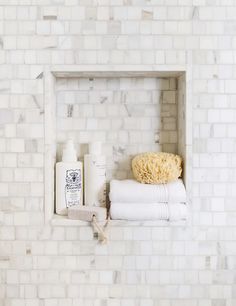 towels and soaps are sitting on the ledge of a white brick wall in a bathroom