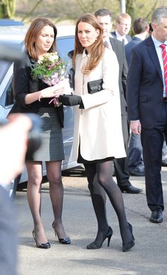 two women in black and white dresses are walking with one woman holding flowers while the other is