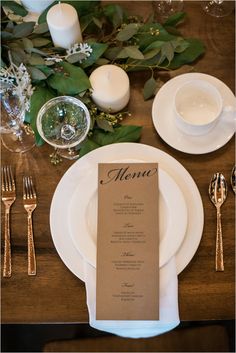 a place setting with silverware and greenery on the table for an elegant dinner