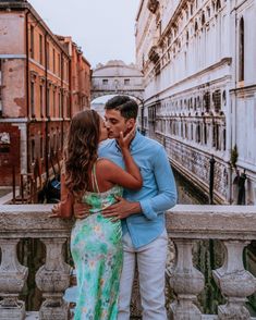 a man and woman standing next to each other in front of a building with buildings