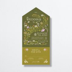 a green and gold wedding card on a white wall with floral designs in the background