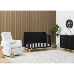 a baby crib in a living room next to a white chair and black dresser