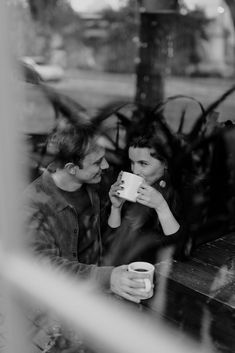 a man and woman sitting at a table drinking coffee