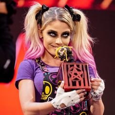 a woman with pink hair and black makeup holding a trophy