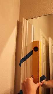 a person measuring the width of a door with tape on it's side and holding a ruler in front of them