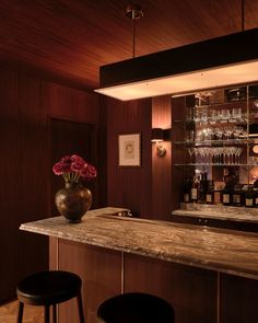 a bar with two stools and a vase filled with flowers