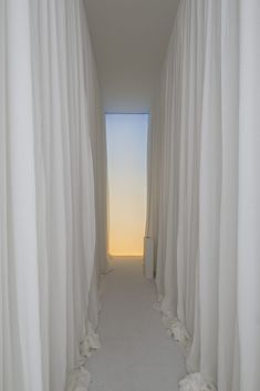 an empty hallway with white drapes leading to the sky