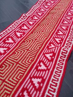 a red and white knitted rug on the floor